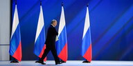 Präsident Putin schreitet auf einer Bühne an vier Flaggen Russlands vorbei