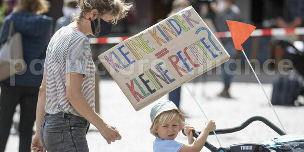 Ein Kind hält ein Plakat mit der Aufschrift "Kleine Kinder, Kleine Rechte?"