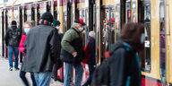 Menschen mit Maske steigen in eine S-Bahn
