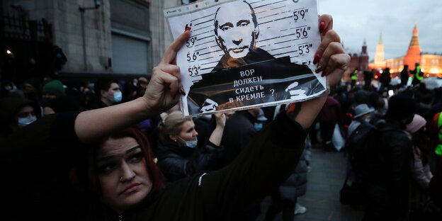 Eine Demonstrantin mit einem Plakat von Putin als Gefangenen.