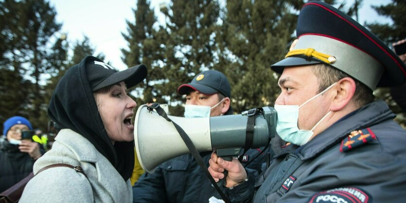 Polizist mit Megafon und Demonstrantin