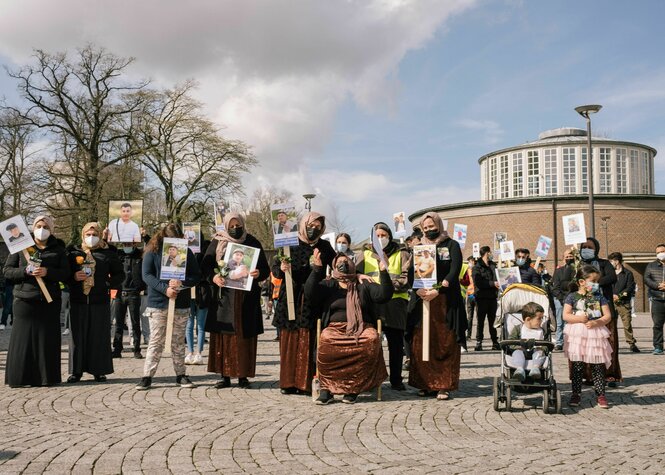 Eine Gruppe von Menschen steht mit Fotos des Verstorbenen auf einem Platz