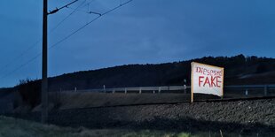 In der Dämmerung steht ein Plakat auf Bahnschienen