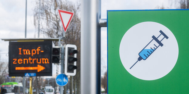 Das große Schild mit einer Spritze darauf und die elektronische Hinweistafel mit dem Wort Impfzentrum weisen den Weg auf dem Messegelände in Hannover.