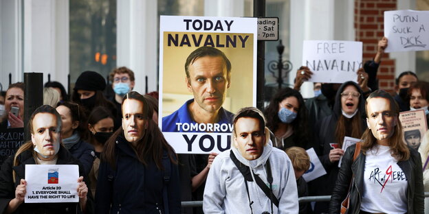 Unterstützer von Nawalny mit einem Plakat und Masken mit seinem Protrait