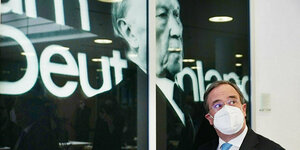 Armin Laschet steht mit Maske vor einem Foto von Konrad Adenauer