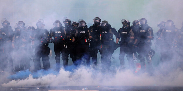 Polisisten stehen im Tränengasnebel