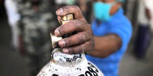 EIne Hand am Ventil einer Sauerstoffflasche im indischen New Delhi