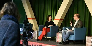 Annalena Baerbock und Ulrich Schulte sitzen auf dem Podium und werden gefilmt