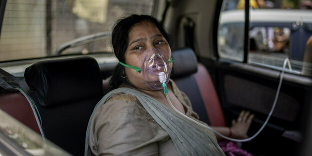 Eine Frau mit Sauerstoffmaske sitzt auf dem Rücksitz eines Autos