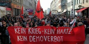 Demonstrierende in Kreuzberg mit einem Transparent, auf dem steht: Kein Krieg, kein Hartz, kein Demoverbot