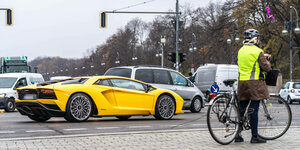 Gelber Lamborghini Sportwagen auf den Straßen von Berlin neg´ben einer Radfahrerin