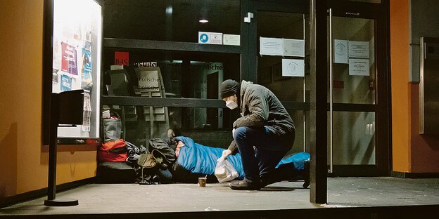 Jürgen Pfeuffer vom Mitternachtsbus der Diakonie Hamburg bringt einem Obdachlosen ein Lunchpaket