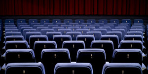 Ein leerer Kinosaal, die Stuhlreihen und die Leinwände sind zusehen
