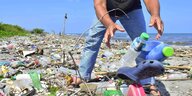 Ein Mann räumt Plastikmüll vom Strand weg