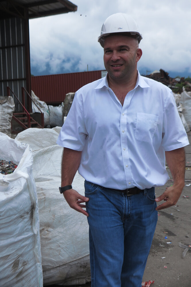 George Gatlin mit weißem Schutzhelm auf der Recyclinganlage Invemacorp