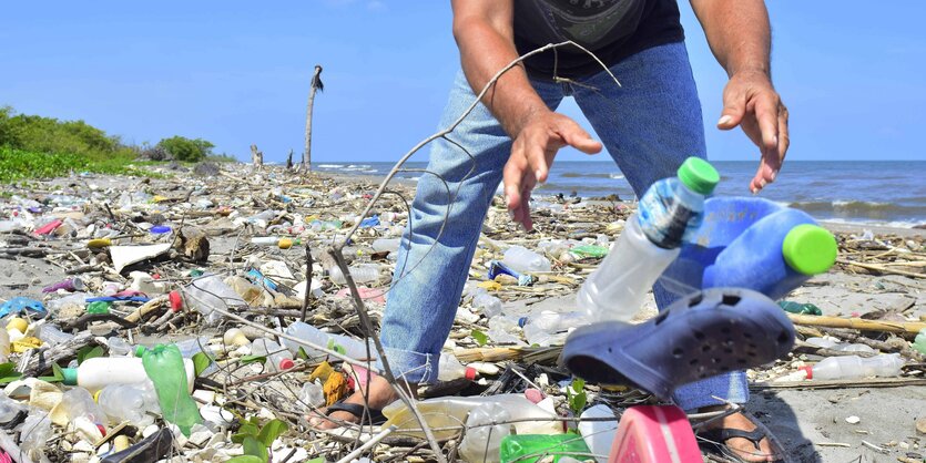 Ein Mann räumt Plastikmüll vom Strand weg