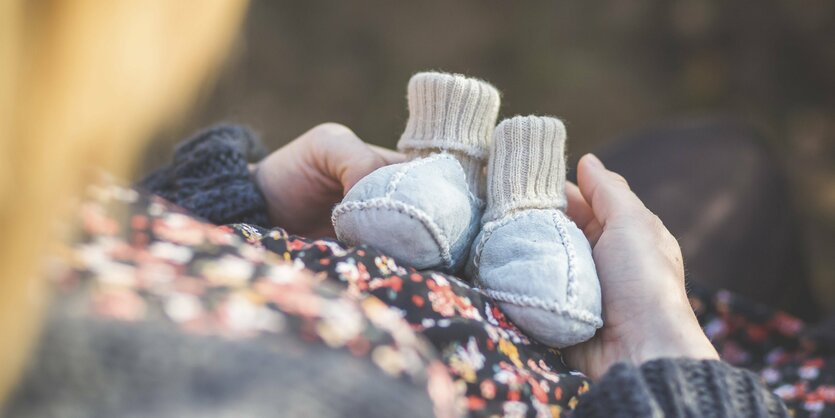 Eine Frau hält Babyschuhe in der Hand