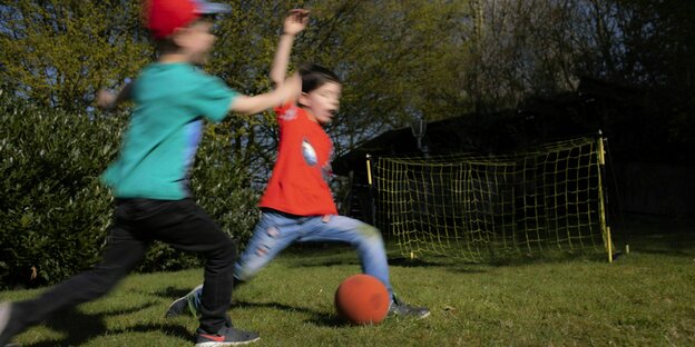 Zwei Jungs spielen m Garten Fussball