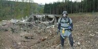 Ein Mann mit Schutzanzug und Gasmaske steht vor dem explodiertens Munitionslager in Vlachovice, Tschechien