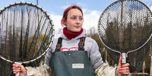 Maria Thamm, Fischwirtin in Ausbildung, steht mit zwei riesigen Käschern vor der Kamera