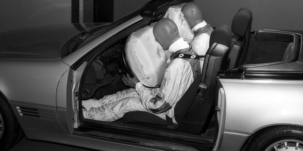 Zwei Crashtestdummys sitzen im Auto, das Gesicht in Airbags gedrückt
