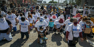 Eine Gruppe Migranten, die T-Shirts mit der Aufschrift «Biden, lass uns bitte rein» tragen, kniet am Grenzübergang und betet