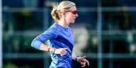 Katharina Steinruck läuft sich in Trainingsklamootten und mit Sonnenbrille warm