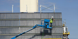 Ein Mann auf einer Hebebühne reinigt eine industrielle Photovoltaik-Alnlage