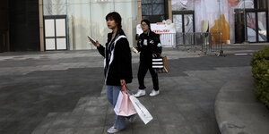 Zwei junge Frauen mit Einkaufstüten und Smartphone