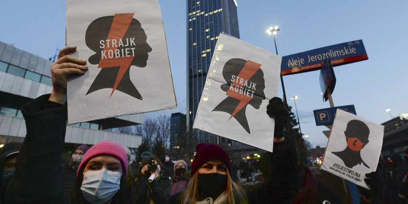 Frauen mit Masken halten Plakate in die Höhe