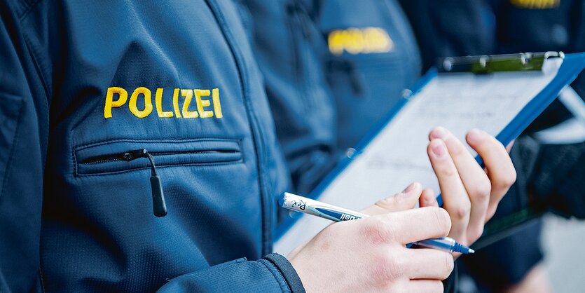 Ein Mensch in Polizeiuniform hält ein Klemmbrett und einen Stift in der Hand.