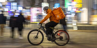 Ein Fahrradkurier mit waremen Speisen im Rukcsack ist Abends in Stuttgart unterwegs
