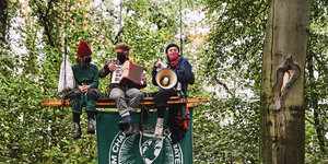 Drei Aktivistinnen sitzen im Wald auf einer Schaukel