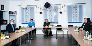 Vier Männer sitzen mit Abstand um einen Tisch
