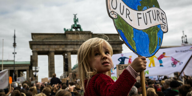 Ein Kind bei einer Demonstration vorm Brandeburger Tor hält ein Schild mit Aufschtift "Our Planet"
