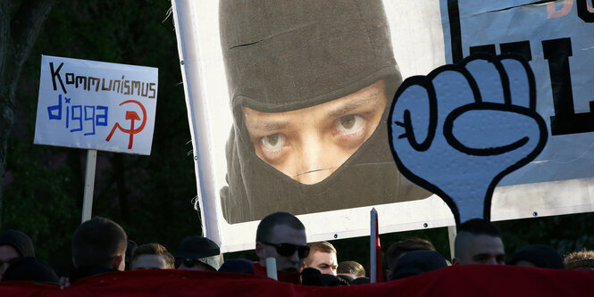 Eine Faust, ein Vermummter auf einem Plakat und das Schild "Kommunismus diggi"