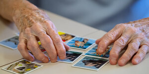 Ein alter Mensch legt Spielkarten auf einem Tisch