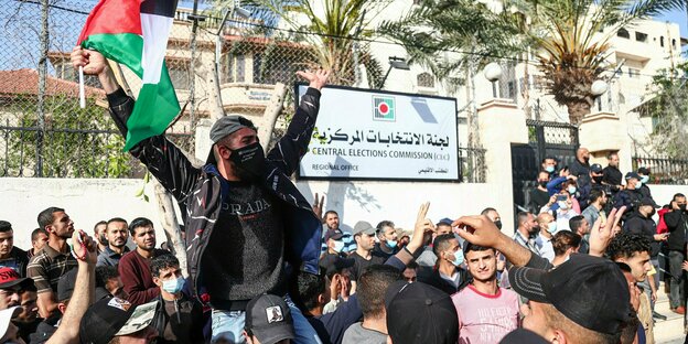 Männer demonstrieren mit Palästina-Flagge vor Büro der Wahlkommission.