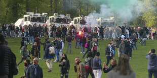 Viele Menschen auf einer Wiese, im Hintergrund mehrere Einsatzfahrzeuge.