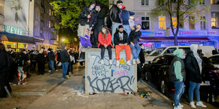 Schaulustige sitzen auf einem Stromkasten in der Sonnenallee in Berlin-Neukölln am 1. Mai 2021