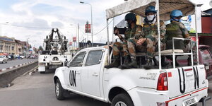Soldaten mit blauen Helmen sitzen auf einem Pick-up