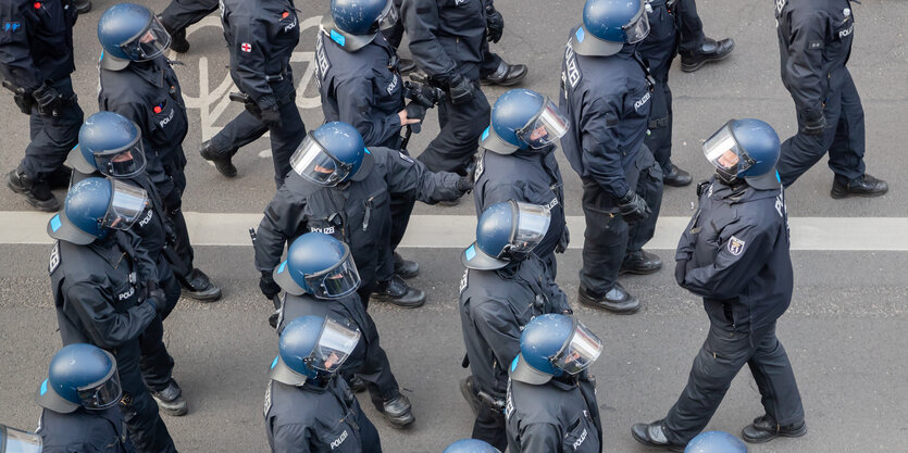 Viele Behelmte Polizist*innen laufen über eine gesperrte Straße