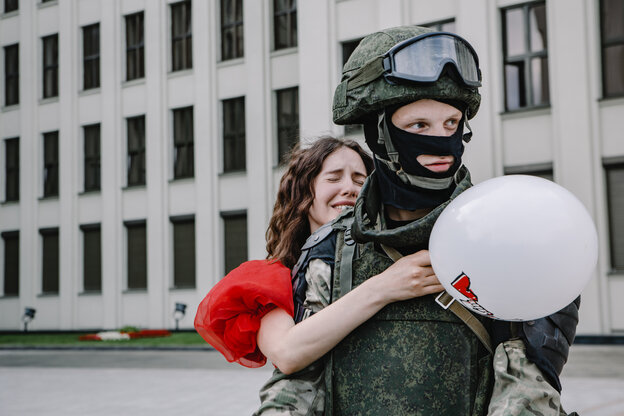 Eine belarussische Demonstrantin umarmt einen Soldaten von hinten.