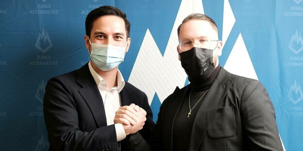 Carlo Clemens und Marvin Neumann posieren mit "handshake" und Mund-Nasenschutz für ein Portraitfoto