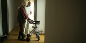 Altenpfleger und Mann mit Rollator