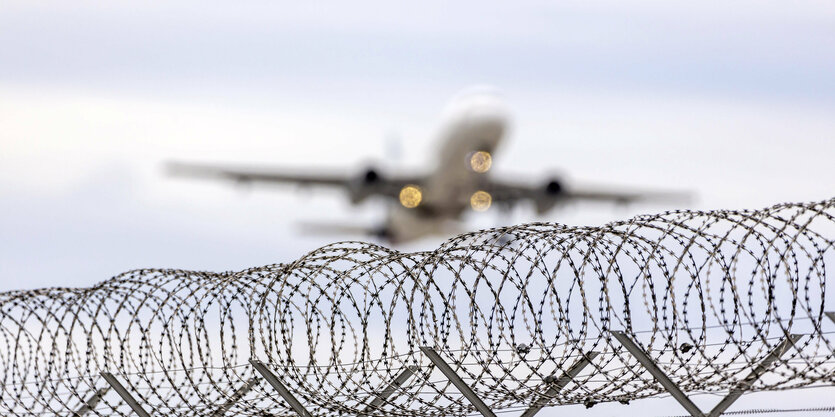 Ein Flugzeug hebt hinter Stacheldraht ab