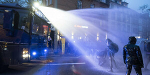 Ein Demonstrant wird in Frankfurt/Main von einem Wasserwerfer besprüht.