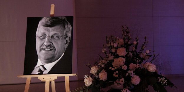 Ein Foto von Walter Lübcke ist neben Blumen während einer Gedenkfeier aufgestellt