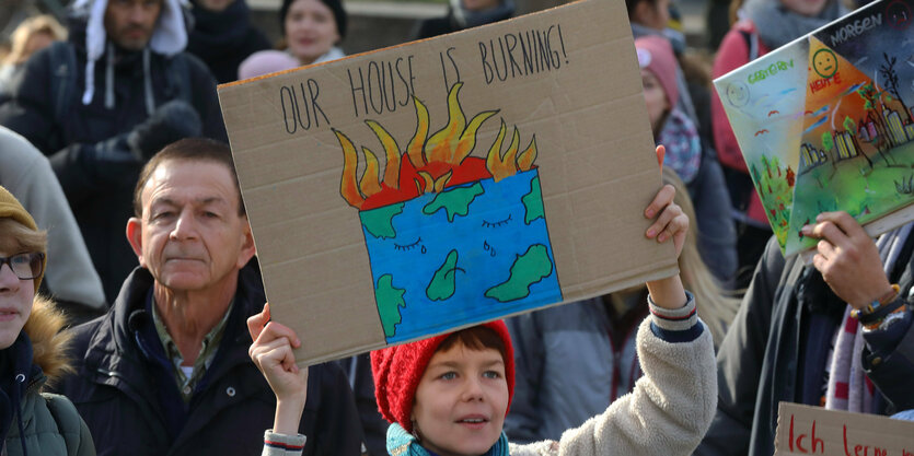 Demonstrantin hält Schild mit der Aufschrift "Demoschild mit der Aufschrift: "OUR HOUSE IS BURNING "